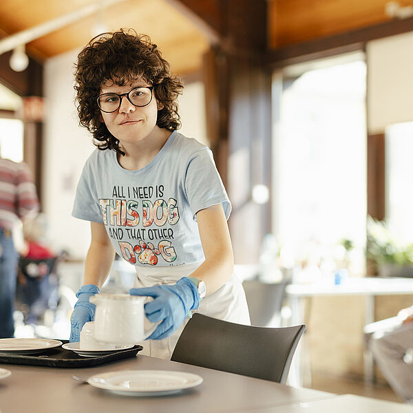 Eine Frau deckt einen Tisch.